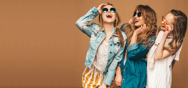 Three laughing women in stylish outfits.